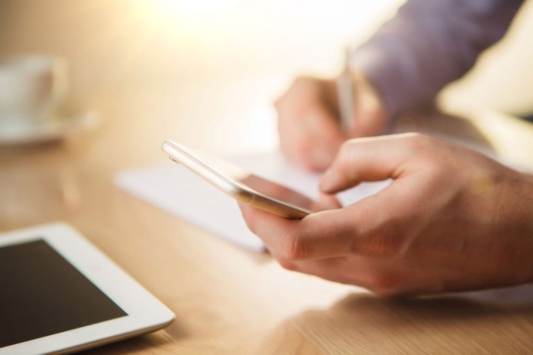 a person sitting at a table using a cell phone.